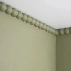 the corner of a room with a light green wall and white ceiling, has round bead trim on it