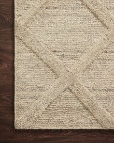 an area rug on a wooden floor with dark brown wood floors and white carpeting