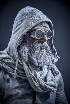 an old man wearing goggles and a scarf on his head is covered in snow