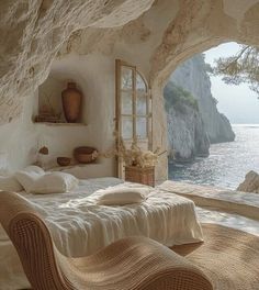 a bed sitting under a window next to a cliff near the ocean in a bedroom