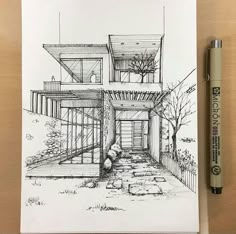 a drawing of a house sitting on top of a wooden table next to a pen