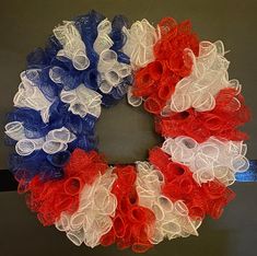 an american flag wreath with red, white and blue tulle flowers in the center