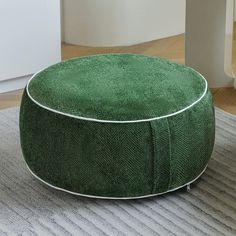 a green round ottoman sitting on top of a rug