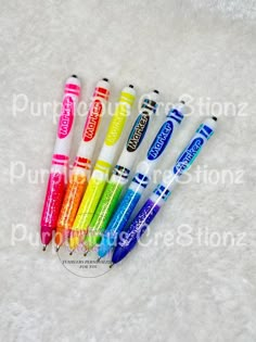 four pens are lined up in a row on a white surface, with the words crayons written below them