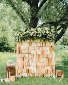 a large wooden block structure with flowers on top and greenery growing out of it