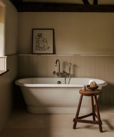 a white bath tub sitting next to a wooden stool