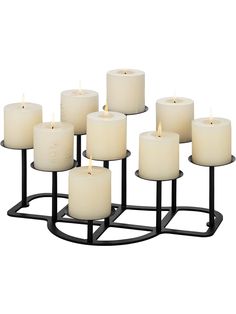 twelve white candles are arranged on a black stand