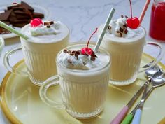 two cups filled with whipped cream and topped with cherries