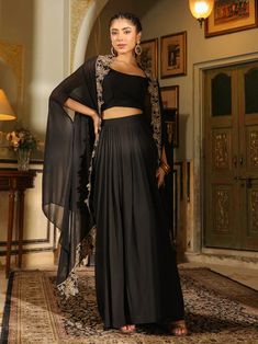 This is beautiful 3-piece set. The set comes with solid crop top has with round-neck, sleeveless teamed with solid skirt and a cape with zari embroidery detailing. 3-piece set Color-Black Work - Zari Embroidery Detailing Blouse Fabric-Georgette Blouse Length - 17 inch Sleeves- Sleeveless Neck-Round Neck Bottom Fabric - Georgette Bottom Length - 45 inch Cape Fabric - Georgette Cape Length - 36 Care-Dry Clean or Hand wash DISCLAIMER - The color of the product may be differ due to screen settings of device. A misprint here and a color drop slip there is the beauty of printing which is not treated as a defect. Fitted Black Sets With Cape Sleeves, Traditional Georgette Sets With Cape Sleeves, Evening Embroidered Choli With Cape Sleeves, Embroidered Choli With Cape Sleeves For Evening, Traditional Sets With Cape Sleeves For Diwali, Traditional Diwali Sets With Cape Sleeves, Elegant Black Set With Cape Sleeves, Elegant Black Sets With Cape Sleeves, Eid Sets With Sheer Dupatta Sleeveless