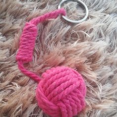 a pink ball of yarn tied to a metal ring on top of a furry surface