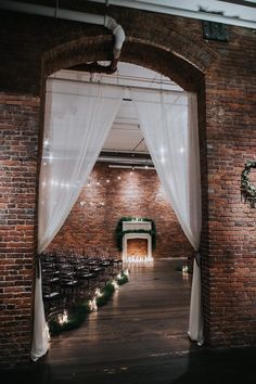 an indoor wedding venue with white drapes and string lights on the ceiling, surrounded by brick walls