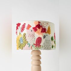 a table lamp with two parrots on it's lampshade that is decorated with flowers and leaves