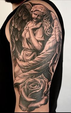 an angel tattoo on the back of a man's arm with roses around it