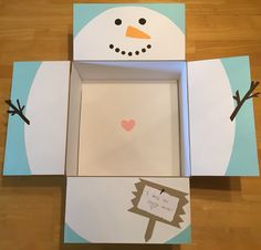 an open box with a snowman cut out and attached to the inside of it