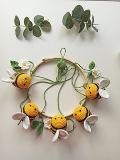 crocheted bees and flowers on a hoop with green leaves next to the hoop