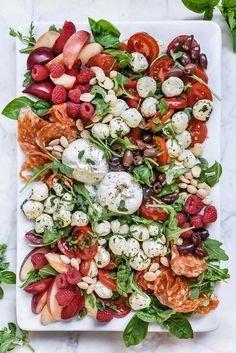 a white plate topped with lots of different types of vegetables and fruits on top of it