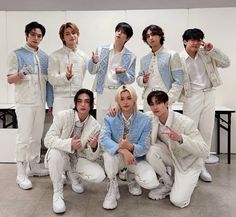 a group of young men standing next to each other in front of a white wall