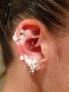 a woman with ear piercings covered in white powdered sugar and sprinkles