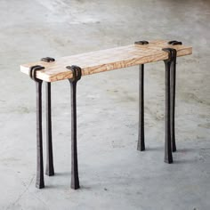 a bench made out of wood and metal legs with two handles on each end, sitting on concrete flooring