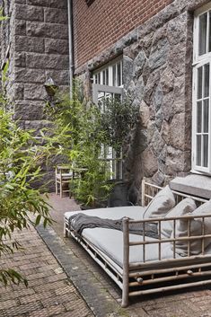 a bed sitting on the side of a building next to a tree and potted plant