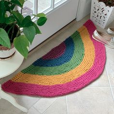 a multicolored rug on the floor next to a potted plant in front of a door