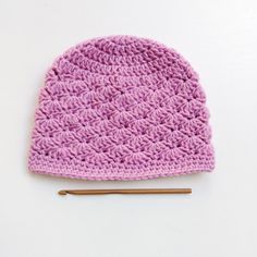 a pink crocheted hat with a knitting needle