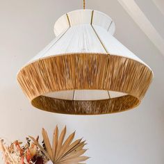 a lamp hanging from the ceiling next to a vase with flowers on it and a plant