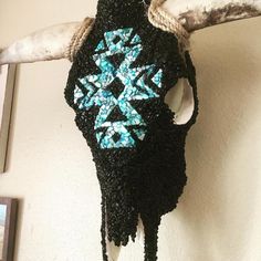 a crocheted cow's head hanging on a wall with blue and white beads