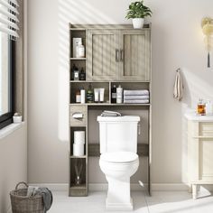 a white toilet sitting in a bathroom next to a wooden shelf filled with bottles and towels