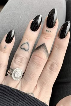 a woman's hand with black and white nail polish on her nails, holding a diamond ring