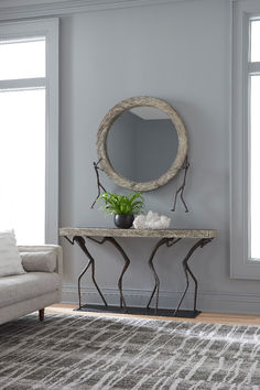 a living room with a couch, mirror and plant on the table in front of it