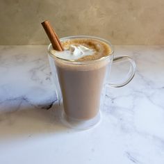 there is a cup of hot chocolate with whipped cream and cinnamon stick in the mug