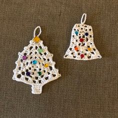 two crocheted christmas ornaments on a brown surface with white strings and colorful beads