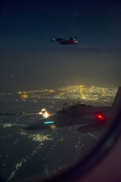 an airplane flying over a city at night with lights on the ground and in the air