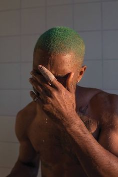 a man with green hair is holding his face in the shower