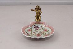 a small figurine sitting on top of a pink and white bowl