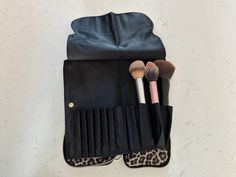 an animal print case holds several makeup brushes and a leopard - print pouch on the floor