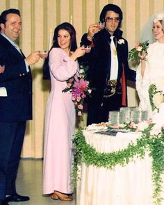 a group of people standing next to each other in front of a table with cake on it