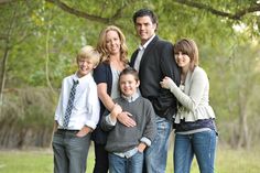 a group of people standing next to each other in front of a tree and grass field