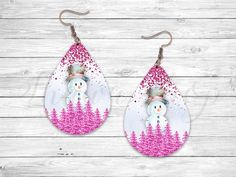 snowman in the woods with pink glitter tear earrings on white wooden planked background