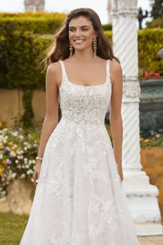 a woman in a white wedding dress smiling at the camera with her hand on her hip