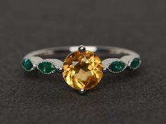 Welcome to my shop, you can find many beautiful gemstone jewelry here, and you also can ask for customized service. Main Stone: yellow citrine, round cut, measures 7X7mm, weight 1.26 caratsAccent Stones: lab created emeraldMetal: 925 sterling silver plated with rhodium. I also can provide metal options such as 14k solid yellow/white/rose goldSetting: four claw basket settingIf you want to know more rings please go to my shop home: https://www.etsy.com/shop/XCjewelryStudio?ref=hdr_shop_menuIt's q Citrine Rings With Accent Stones, Topaz Citrine Ring With Center Stone, Round Topaz Ring With Citrine Center Stone, Citrine Birthstone Ring With Accent Stones, Elegant Yellow Solitaire Birthstone Ring, Yellow Topaz Round Ring, Yellow Citrine Solitaire Birthstone Ring, Yellow Topaz Promise Ring, Round Cut, Yellow Sapphire Round Promise Ring