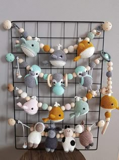 there are many crocheted animals hanging on the wall next to a wire rack