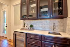 a kitchen with wooden cabinets and marble counter tops, along with hardwood flooring that matches the white walls