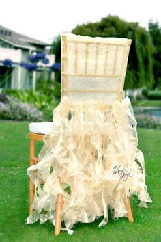 a chair that is sitting in the grass with ruffles on it's back