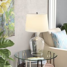 a glass table topped with a lamp next to a couch