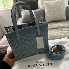 Coach Field Tote 22in Denim Collection. New With Tags. Has Dustbag. Has Strap. Signature Denim And Refined Calf Leather Inside Zip Pocket Snap Closure, Fabric Lining Handles With 4" Drop Detachable Strap With 24 1/2" Drop For Shoulder Or Crossbody Wear Four Protective Feet At Base 8 3/4" (L) X 8 1/4" (H) X 4 3/4" (W) Style No. Cj853 Luxury Denim Tote Bag, Blue Denim Bag With Top Carry Handle, Luxury Denim Bags For Shopping, Blue Denim Bag With Dust Bag Included, Luxury Blue Denim Bag, Blue Denim Shoulder Bag With Branded Hardware, Everyday Denim Blue Bags With Branded Hardware, Designer Denim Tote Shoulder Bag, Designer Denim Tote Bag