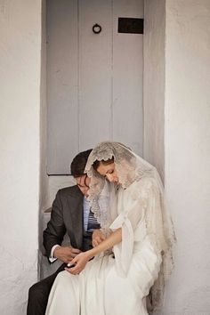 a bride and groom are sitting on the steps in front of an open door together