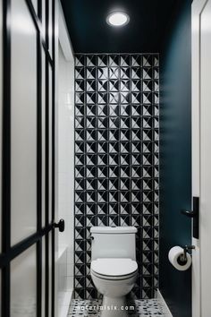 Modern bathroom with geometric black and white patterned tiles behind the toilet. Green Painted Walls