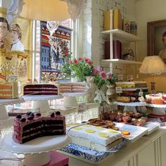 a table filled with cakes and desserts on top of it next to a window